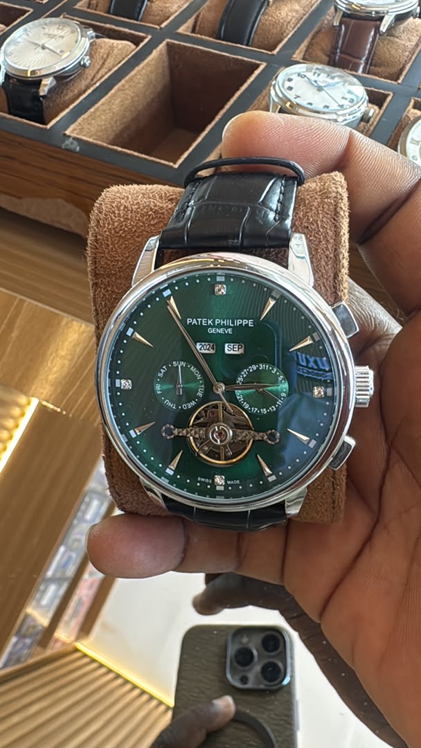 Green dial luxury wristwatch held in hand